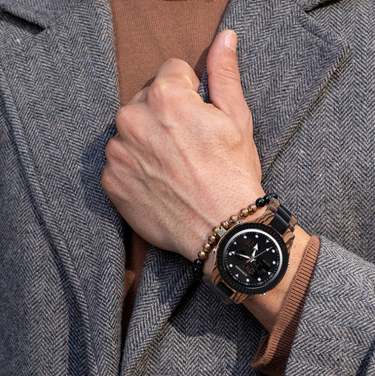 Hand wearing a wooden watch with a detailed face, against a textured gray coat background.