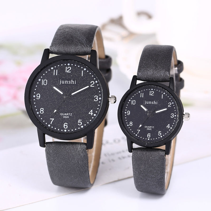 Two black wristwatches with gray straps on a light background