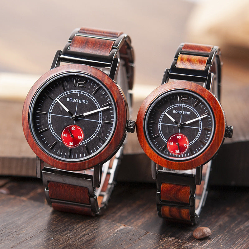 Two wooden watches with black faces and red accents on a wooden surface.