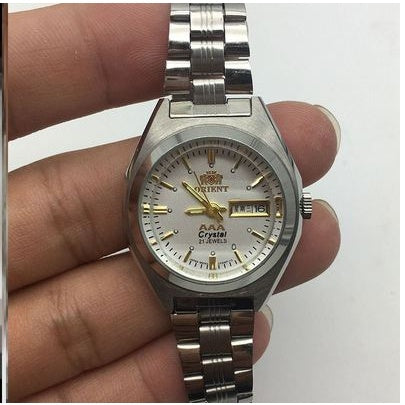 Silver wristwatch held in a hand against a white background