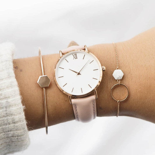 Wrist wearing a rose gold watch with matching bracelet on a light background