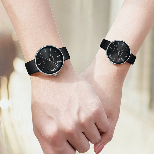 Two wrists wearing matching black wristwatches against a blurred background
